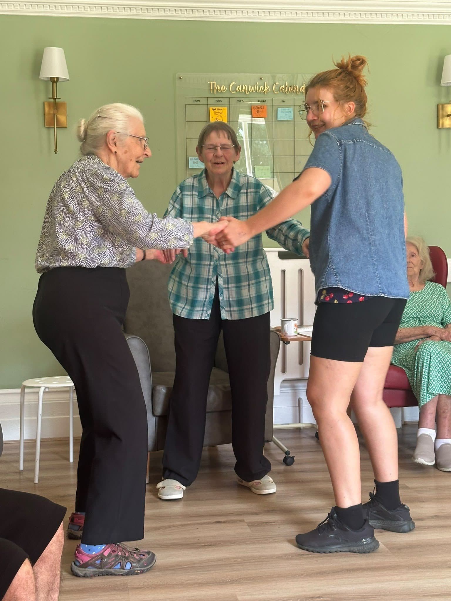 Residents and a carer dancing together during an activity